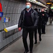 A man wears a mask while travelling on the London Underground