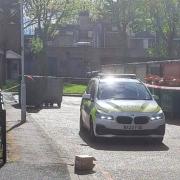A police officer stands guard as an area outside Charlbury House, Little Ilford, is cordoned off after a man's body lay slumped in the street for hours
