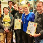 Phil Cooke (holding left certificate) and Alison Taffs (in blue) pictured after The Hop Inn was awarded London Cider Pub of the Year 2024