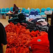 Nurses Charleen and Deepika displaying a pile of free school uniforms to give away