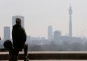 A man sitting on Primrose Hill looks at smog over London