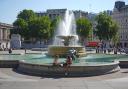 People sit by the fountains in Trafalgar Square, central London.