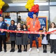 Team GB Olympian Toby Harries and store manager Giuseppe Daniello cut the ribbon at Aldi with children from North Beckton Primary School