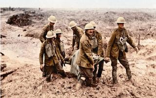 British soldiers carry a wounded comrade to safety through the mud of the First World War